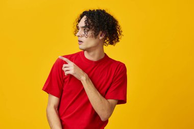 Kırmızı tişörtlü komik beyaz adam sarı stüdyo arka planında yalnız poz veriyor. Reklamcılık için bedava olan en iyi teklif. Günlük kavramlar için duygular