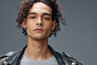 Gri stüdyo arka planında izole edilmiş şık, bronzlaşmış deri ceketli adam portresi. Güzel moda teklifi. Büyük Mevsimlik Satış Yeni Koleksiyon konsepti. İlan için alanı kopyala