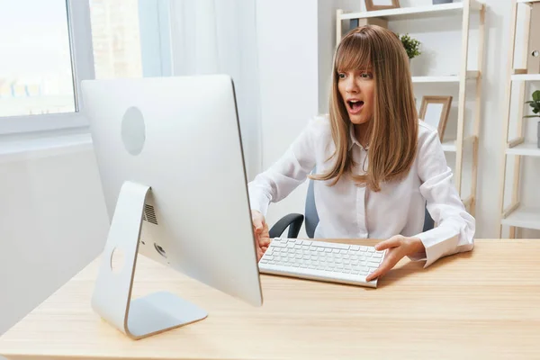 Shocked excited blonde businesswoman hold keyboard confused after computer software crash error at workplace in modern office. Upset director work online in financial corporation. Copy space