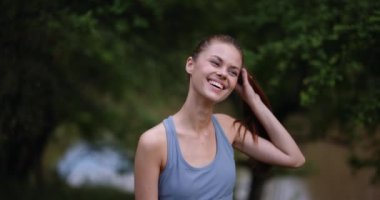 Genç bir kadın saçlarına cilveli bir şekilde dokunuyor ve kameraya bakarak tatlı bir gülümseme sergiliyor. Yüksek kalite 4k görüntü