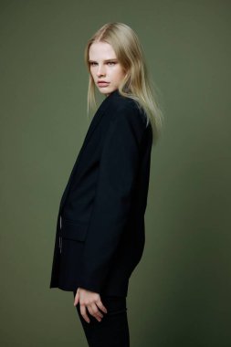 Stüdyoda yeşil zeytin arka planda poz veren takım elbiseli genç bir kız bir giyim markası için mükemmel bir pankart. Yeni konsept koleksiyonu. Yüksek kalite fotoğraf