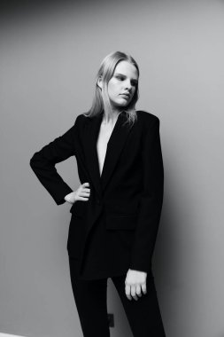 Takım elbiseli zarif bir kız poz verir ve eli belinde kameraya bakar. Yüksek kalite fotoğraf