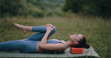Bir kadın doğada jimnastik paspası üzerinde egzersiz yapar ve kaslarını spor küplerine pompalar. Spor Yaşam Tarzı. Yüksek kalite 4k görüntü