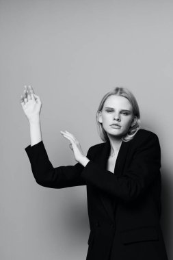 Model kız elleri yukarıda stüdyoda klasik bir ceketle siyah beyaz poz veriyor. Yüksek kalite fotoğraf