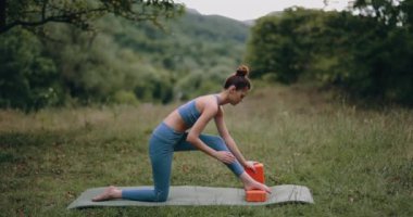 Bir kadın dışarıda jimnastik minderinde egzersiz yapar ve bacak kaslarını spor küpleri üzerine gerer. Spor Yaşam Tarzı. Yüksek kalite 4k görüntü