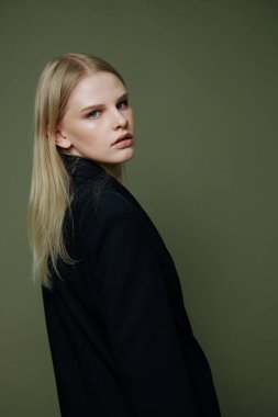 Güzel, çekici bir kız, yarı yarıya kameraya çevrilmiş bir şekilde omzunun üstünden bakıyor. Kostüm ve giyim markası için harika bir afiş. Sıcak satış teklifi. Yüksek kalite fotoğraf