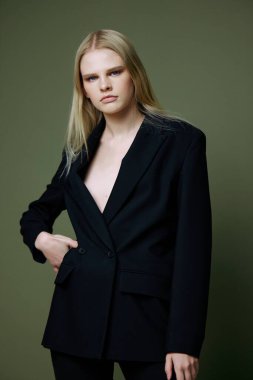 Klasik takım elbiseli güzel sarışın bir kadın yeşil arka planda stüdyoda poz veriyor. Yüksek kalite fotoğraf