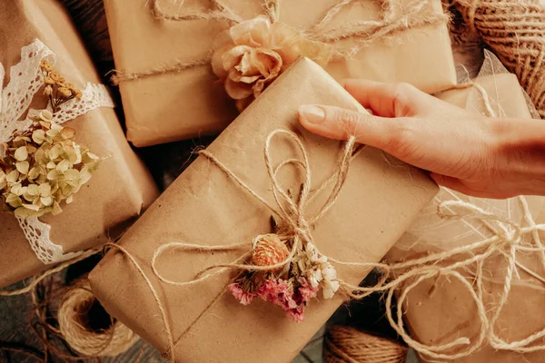 Boho romantische Floristin dekoriert Geschenke in Schachteln mit umweltfreundlichen natürlichen Materialien. — Stockfoto