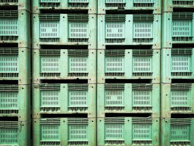 Eski ve hasarlı yeşil renk yığını kullanılmış plastik ambalaj sandıkları arka planı. Tarım ürünleri için boş kutuların duvarı.