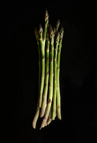 Raw green asparagus sticks on a black background. — стоковое фото