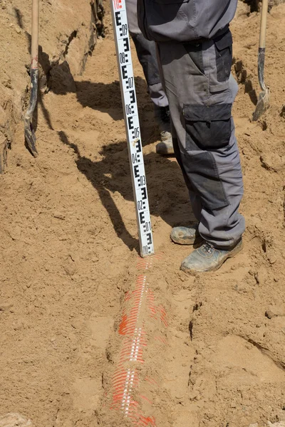 Trabajador instalando tubería de alcantarillado en trinchera arenosa — Foto de Stock