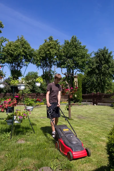 Pojke slåtter trädgården — Stockfoto