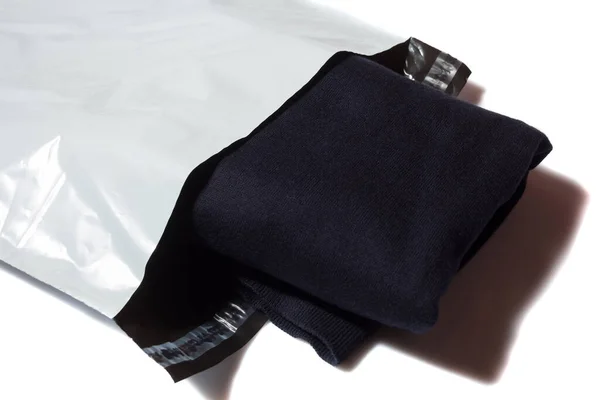 白色背景的白色塑料邮包中的蓝色套头衫 — 图库照片