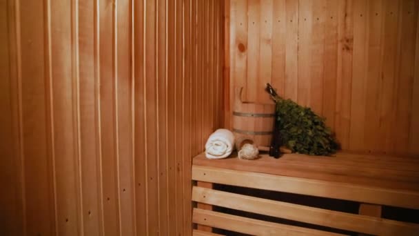 伝統的なロシアの古い浴場SPAの概念。室内詳細伝統的なサウナ付きのフィンランド式サウナスチームルームでは、洗面台白樺のほうきタオルアロマオイルを設定します。田舎の村のバスコンセプトをリラックス. — ストック動画