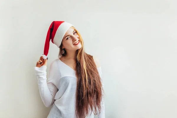 漂亮的女孩 留着红头发 戴着圣诞红帽 被白色背景隔离 看上去快乐而兴奋 年轻女人的肖像 真实的情感 圣诞佳节快乐 — 图库照片