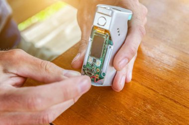 Erkek eli, e-sıvı yapmak için modern buharlaştırıcı e-sigara aleti tamir ediyor. Elektronik ekipman mekanik buharlaştırma cihazının bakımı. Vaper aygıt onarım servisi