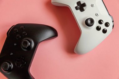 Beyaz ve siyah iki joystick oyun sahası, pastel pembe renkli pin-up arka planda oyun konsolu. Bilgisayar oyunu yarışması video oyunu kontrol yüzleşmesi konsepti. Siber uzay sembolü