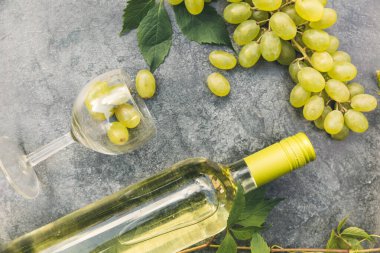 Şişe beyaz şarap, yeşil şarap, şarap kadehi ve eski gri taş masa zemininde olgun üzüm. Şarap dükkanı şarap dükkanı ya da şarap tatma konsepti