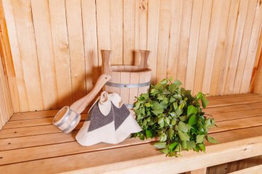 Geleneksel eski Rus hamamı SPA konsepti. İçişleri, geleneksel sauna aksesuarları ve huş ağacı süpürgesi kepçesiyle Finlandiya sauna saunası saunasının ayrıntılarını veriyor. Rahatlayın köy banyosu konsepti.