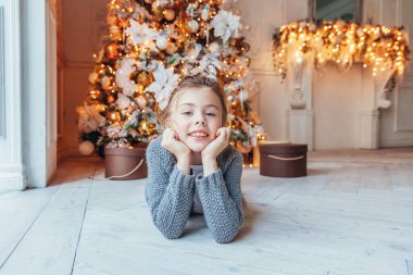 Noel arifesinde Noel ağacının yanında hediye kutusu olan küçük bir kız. Açık renk yatak odalı, kış dekorasyonlu küçük bir çocuk. Mutlu bir aile. Noel Yeni Yıl Kutlama Konsepti Zamanı