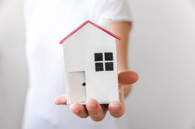 Beyaz arka planda izole edilmiş oyuncak model evi tutan kadın. Gayrimenkul ipoteği sigorta hayali ev konsepti. Kiralık ev, aile hayatı, iş yeri gayrimenkul teklifi