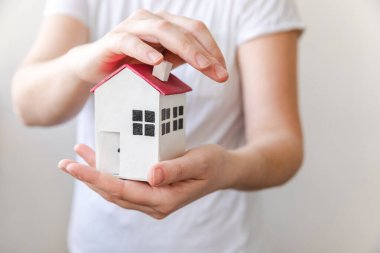 Beyaz arka planda izole edilmiş oyuncak model evi tutan kadın. Gayrimenkul ipoteği sigorta hayali ev konsepti. Kiralık ev, aile hayatı, iş yeri gayrimenkul teklifi