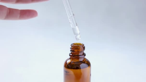 Essentiële olie die van pipet naar fles valt. Essentie vloeibare cosmetische. Druppelglazen fles met vloeibaar cosmetisch serum. Siroop, parfum, aromatherapie concept. Schoonheidsbehandeling — Stockvideo