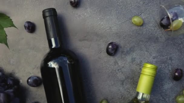 Draufsicht auf Flasche Rot- und Weißwein, grüne Rebe, Weinglas und reife Trauben auf dunklem Steintischhintergrund. Vinothek Weinbar Weingut oder Weinverkostungskonzept. — Stockvideo