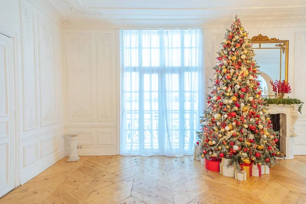 Quarto interior decorado de Natal clássico, árvore de Ano Novo com decorações vermelhas e douradas. Moderno estilo clássico branco apartamento de design de interiores com lareira e árvore de Natal. Véspera de Natal em casa. — Fotografia de Stock