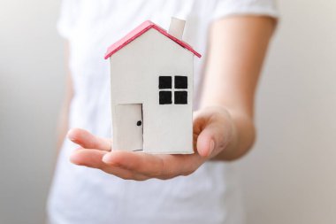 Beyaz arka planda izole edilmiş oyuncak model evi tutan kadın. Gayrimenkul ipoteği sigorta hayali ev konsepti. Kiralık ev, aile hayatı, iş yeri gayrimenkul teklifi.