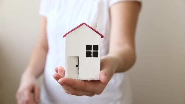 Vrouw hand houden speelgoed modelhuis geïsoleerd op witte achtergrond. Onroerend goed hypotheek verzekering droom huis concept. Aanbod van aankoop huurhuis, gezinsleven, zakelijk onroerend goed. — Stockvideo