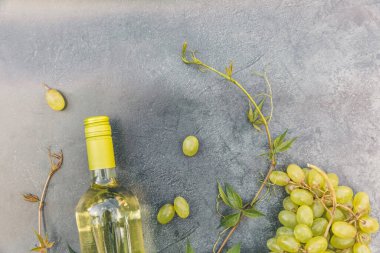 Beyaz şarap, yeşil sarmaşık ve olgun üzümle klasik gri masa arkaplanının en üst görüntüsü. Şarap dükkanı şarap dükkanı ya da şarap tatma konsepti.