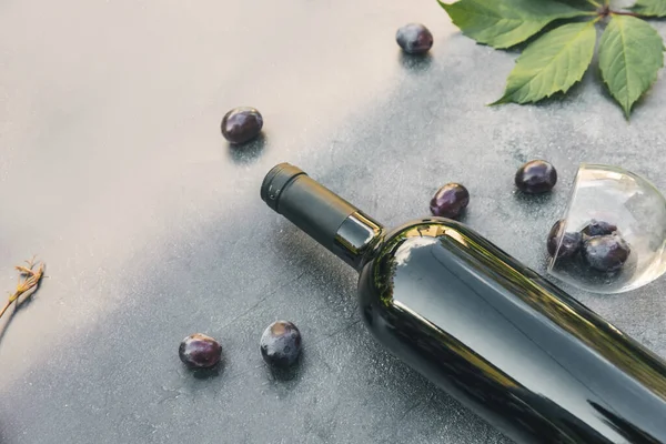 Bir şişe kırmızı şarap, yeşil üzüm, şarap kadehi ve olgun üzümlü eskimiş taş masa arkaplanı. Metin için üst görünüm kopyalama alanı. Şarap dükkanı şarap dükkanı ya da şarap tatma konsepti.