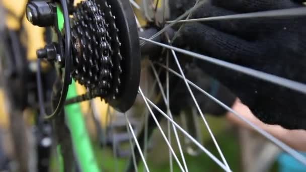 Mecánico de bicicletas reparaciones hombre bicicleta en taller de reparación de bicicletas, al aire libre. Mano de ciclista ciclista examina, fija el sistema de transmisión de ciclo moderno. Mantenimiento de bicicletas, concepto de tienda de deporte. — Vídeo de stock