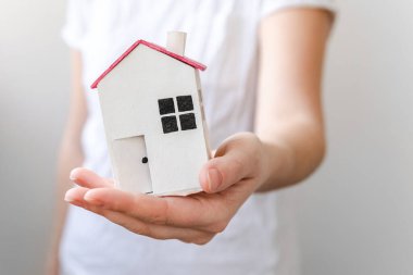 Beyaz arka planda izole edilmiş oyuncak model evi tutan kadın. Gayrimenkul ipoteği sigorta hayali ev konsepti. Kiralık ev, aile hayatı, iş yeri gayrimenkul teklifi.