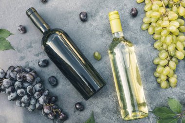 Şişe kırmızı ve beyaz şarap, yeşil şarap, şarap kadehi ve olgun üzümlü eskimiş taş masa arkaplanı. Şarap dükkanı şarap dükkanı ya da şarap tatma konsepti.