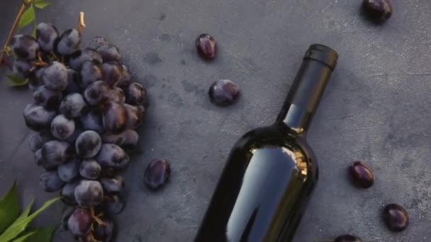 Vista superior de la botella de vino tinto, vid verde, vino y uva madura sobre fondo de mesa de piedra oscura vintage. Vino tienda vinoteca bodega o concepto de degustación de vinos. — Vídeo de stock