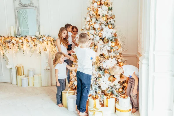 Ευτυχισμένη οικογενειακή μητέρα και πέντε παιδιά στολίζουν το χριστουγεννιάτικο δέντρο την παραμονή των Χριστουγέννων στο σπίτι. Mom κόρες γιους στο φως δωμάτιο με διακόσμηση το χειμώνα. Χριστούγεννα Πρωτοχρονιά για γιορτή — Φωτογραφία Αρχείου