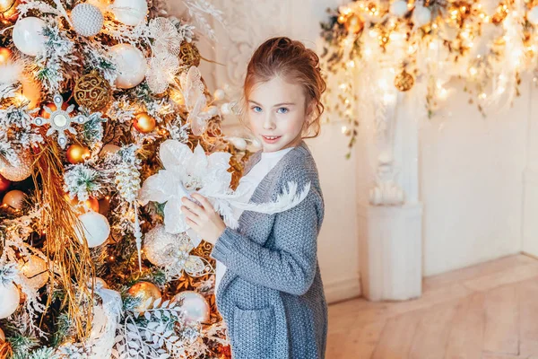 クリスマスツリーを飾る小さな女の子は自宅で前夜に。冬の装飾が施された明るい寝室の若い子供。家庭で幸せな家族。クリスマスお祝いのコンセプトのための12月の時間. — ストック写真