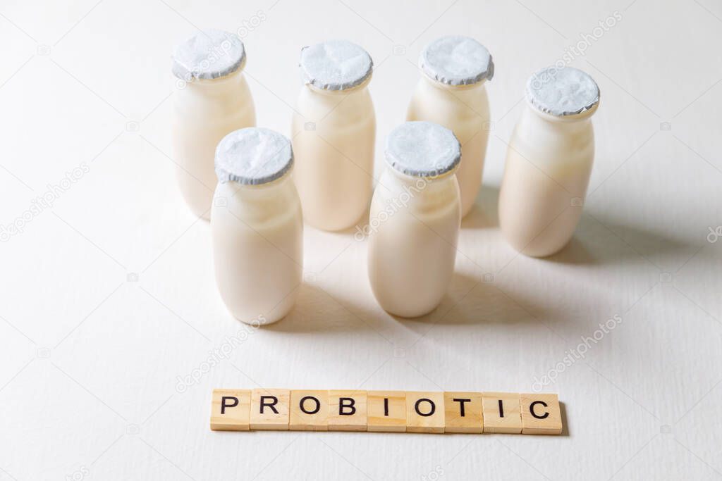 Small bottles with probiotics and prebiotics dairy drink on white background. Production with biologically active additives. Fermentation and diet healthy food. Bio yogurt with useful microorganisms.