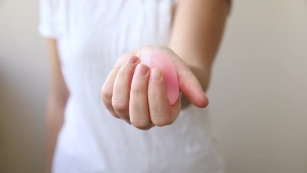 ピンクの月経カップを保持する女性の手は白い背景に隔離されました.生理中の女性の近代的な代替エコ婦人科衛生.女の子の手の血のための容器. — ストック動画