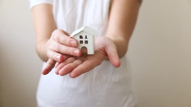 Vrouw hand houden speelgoed modelhuis geïsoleerd op witte achtergrond. Onroerend goed hypotheek verzekering droom huis concept. Aanbod van aankoop huurhuis, gezinsleven, zakelijk onroerend goed. — Stockvideo