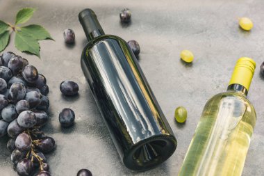 Şişe kırmızı ve beyaz şarap, yeşil şarap, şarap kadehi ve olgun üzümlü eskimiş taş masa arkaplanı. Şarap dükkanı şarap dükkanı ya da şarap tatma konsepti