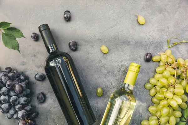 Stock image Top view of bottle red and white wine, green vine, wineglass and ripe grape on vintage dark stone table background. Wine shop wine bar winery or wine tasting concept.