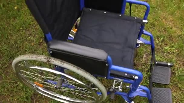 Порожній інвалідний візок стоїть у лікарняному парку, чекаючи на пацієнтські послуги. Колісний стілець для людей з інвалідністю, припаркований на відкритому повітрі. Доступний для людей з інвалідністю. Медична концепція охорони здоров'я . — стокове відео