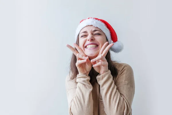 Belle fille en chapeau rouge Père Noël isolé sur fond blanc. Portrait hivernal de jeune femme. Joyeux Noël et Nouvel An concept de vacances. — Photo