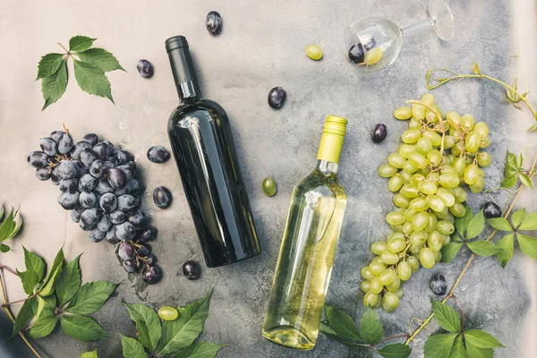 Şişe kırmızı ve beyaz şarap, yeşil şarap, şarap kadehi ve olgun üzümlü eskimiş taş masa arkaplanı. Şarap dükkanı şarap dükkanı ya da şarap tatma konsepti.