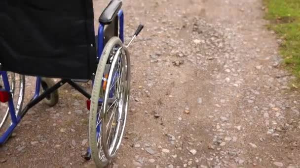 Пустое инвалидное кресло, стоящее на дороге и ожидающее обслуживания пациентов. Коляска для людей с ограниченными возможностями припаркована на открытом воздухе. Доступно для людей с ограниченными возможностями. Медицинская концепция. — стоковое видео
