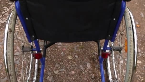 환자의 도움을 기다리며 길가에 서 있는 텅 빈 휠체어. 야외에 주차 된 장애 인을 위한 휠체어. 장애가 있는 사람을 위해 사용 할 수있다. 의료 상의 개념. — 비디오