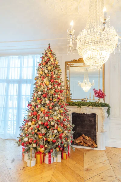 Quarto interior decorado de Natal clássico, árvore de Ano Novo com decorações vermelhas e douradas. Moderno estilo clássico branco apartamento de design de interiores com lareira e árvore de Natal. Véspera de Natal em casa. — Fotografia de Stock